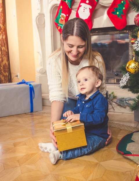 Uśmiechnięta Matka I Jej Synek Z Prezentem świątecznym Na Podłodze W Salonie