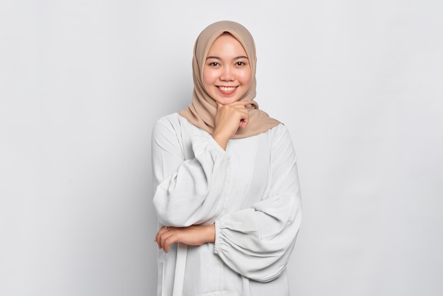 Uśmiechnięta młoda azjatycka muzułmanka czuje się pewnie i radośnie na białym tle na białym tle