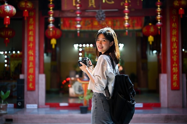 Uśmiechnięta młoda azjatycka turystka zwiedzająca i odwiedzająca piękną chińską świątynię