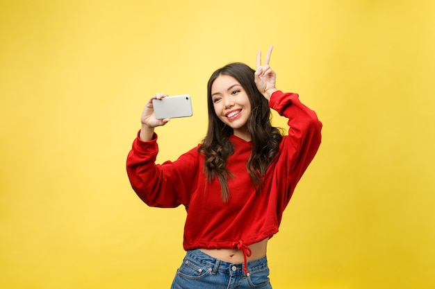 Uśmiechnięta młoda dziewczyna robi selfie zdjęcie na smartfonie