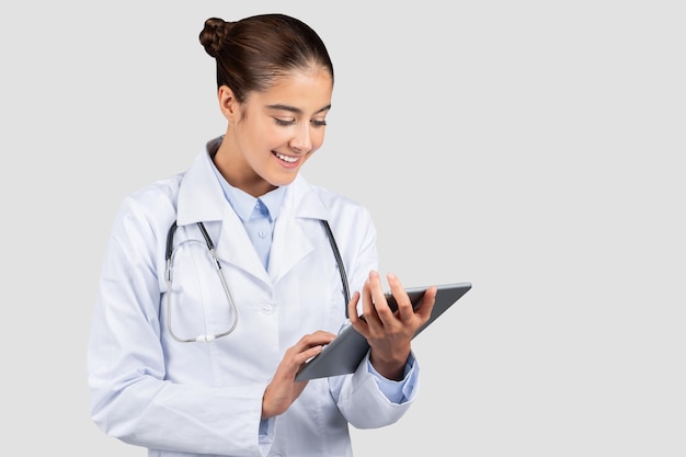 Uśmiechnięta młoda europejska kobieta profesjonalny lekarz lub stażysta pisze na tabletu rozmawia