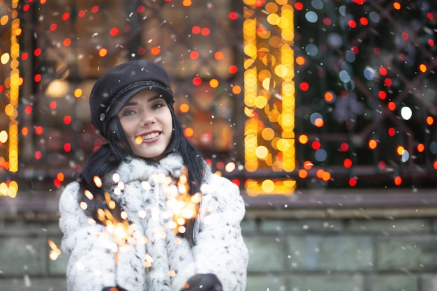Uśmiechnięta młoda kobieta korzystających z ferii zimowych z musujące światła. Pusta przestrzeń