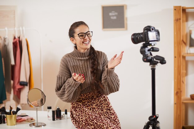 Uśmiechnięta Młoda Kobieta Opowiada Do Kamery W Studio Kosmetyczne