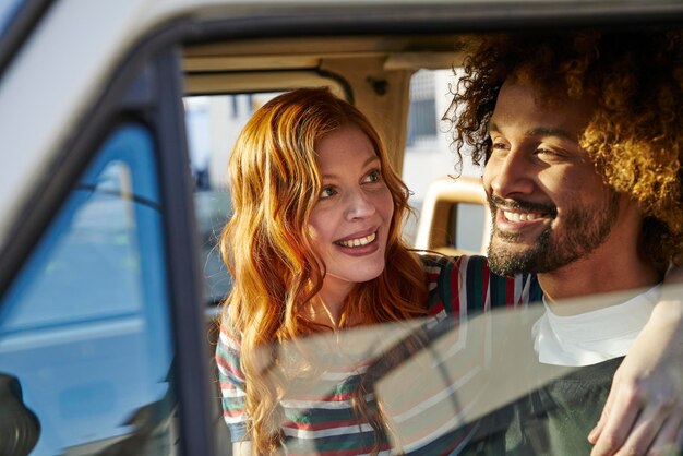 Uśmiechnięta młoda kobieta patrząca na chłopaka w samochodzie