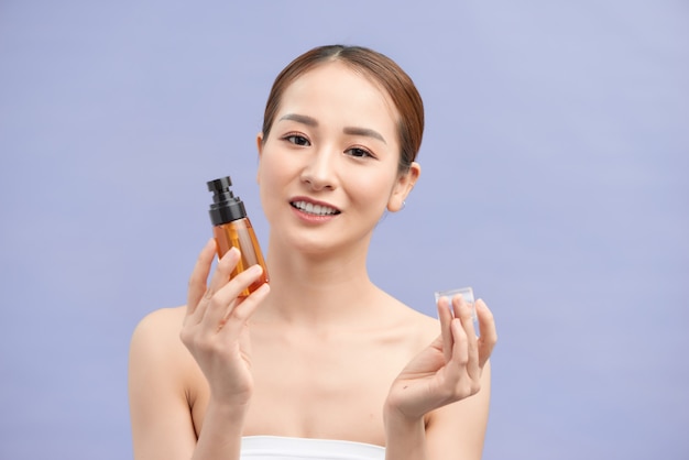 Uśmiechnięta młoda kobieta pokazuje produkty do pielęgnacji skóry