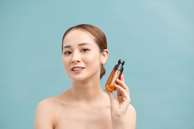 Uśmiechnięta młoda kobieta pokazuje produkty do pielęgnacji skóry