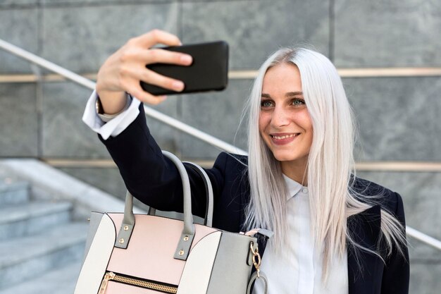 Zdjęcie uśmiechnięta młoda kobieta robi selfie na schodkach w mieście