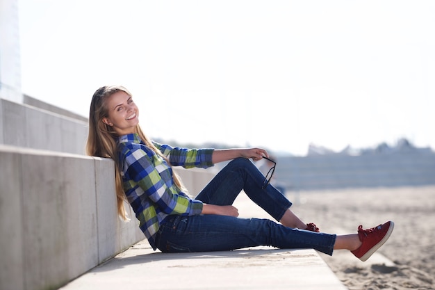 Uśmiechnięta młoda kobieta siedzi outdoors