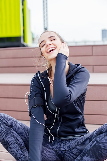 Zdjęcie uśmiechnięta młoda kobieta słucha muzyka z smartphone i hełmofonami