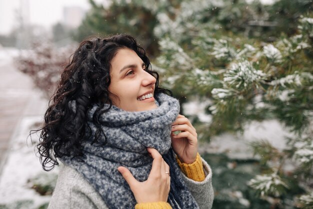 Zdjęcie uśmiechnięta młoda kobieta stoi w mroźnym śnieżnym zimowym parku.