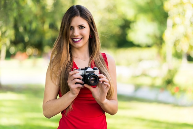 Uśmiechnięta młoda kobieta trzyma rocznik kamerę