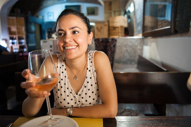 Uśmiechnięta młoda kobieta trzymająca szklankę w restauracji
