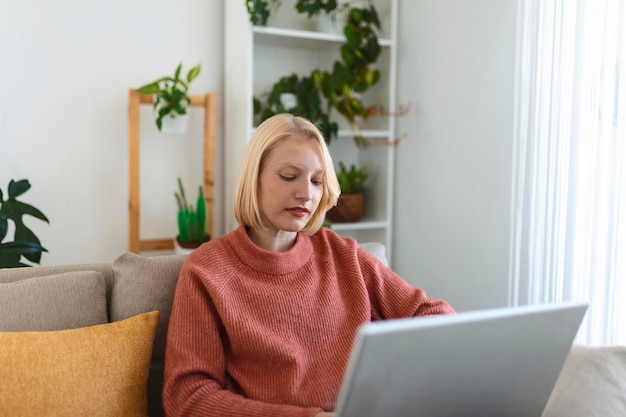 Uśmiechnięta młoda kobieta za pomocą laptopa w domu, patrząc na ekran, rozmawiając, mając na sobie bezprzewodowy zestaw słuchawkowy mający wideokonferencję trener biznesowy korepetycje przez kamerę internetową szkolenie online koncepcja ecoaching