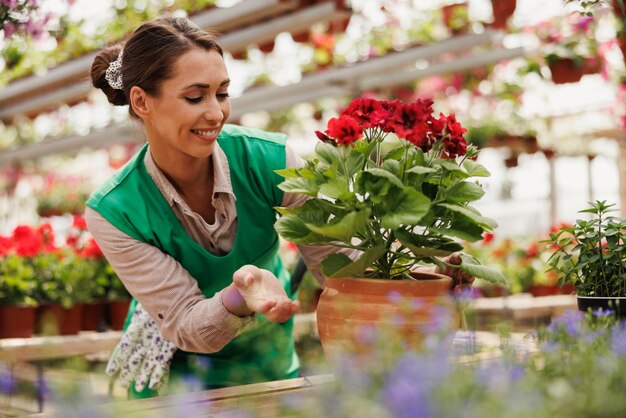 Uśmiechnięta młoda kwiaciarnia pracująca z kwiatami w centrum ogrodniczym. Kobieta przedsiębiorca.