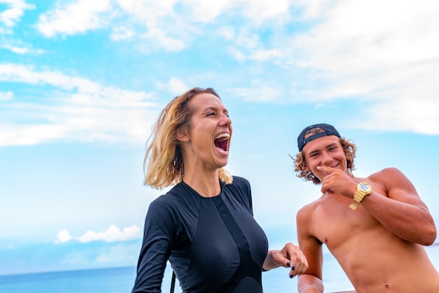 Uśmiechnięta młoda para aktywnych surferów relaks na plaży po sporcie.