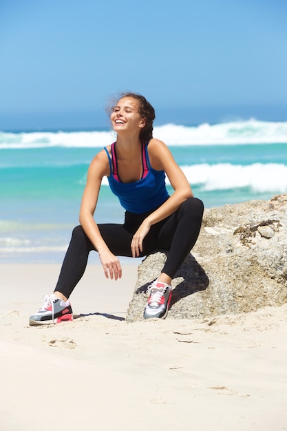 Uśmiechnięta młoda sporty kobieta relaksuje przy plażą