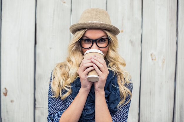 Uśmiechnięta modna blondynka pije kawę outdoors