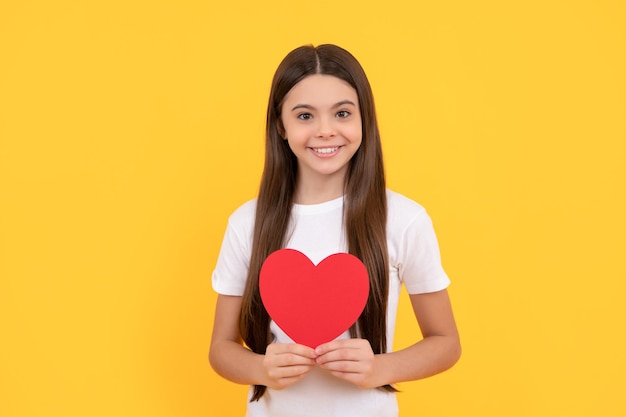 Uśmiechnięta nastolatka trzymająca walentynkowe serce na żółtym tle walentynkowa wyprzedaż