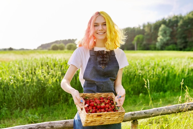 Uśmiechnięta nastolatka z truskawkami w koszu ogród natura tło zdrowa naturalna organiczna witamina żywność sezon truskawkowy