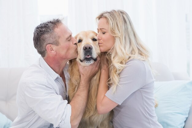 Uśmiechnięta Para Całuje Ich Golden Retriever Na Leżance