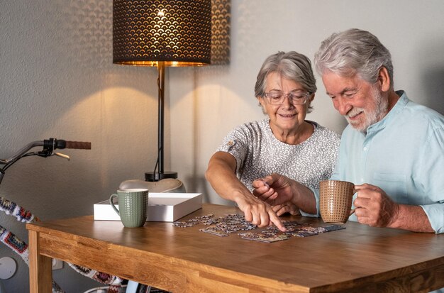 Uśmiechnięta para starszych robi układanka w domu na drewnianym stole. Zabytkowy rower w rogu