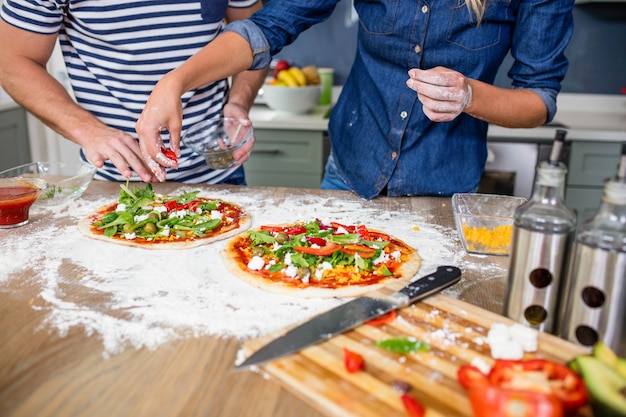 Uśmiechnięta pary narządzania pizza w kuchni