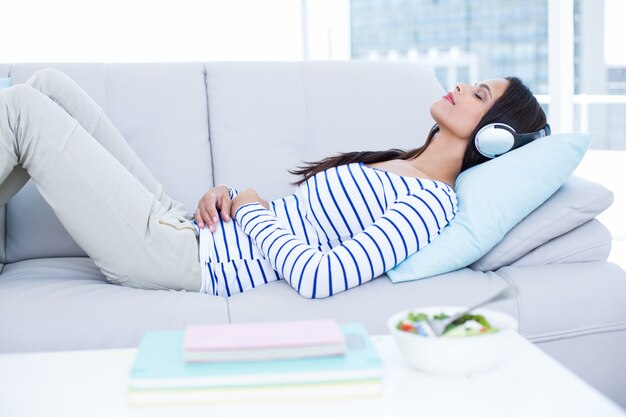 Uśmiechnięta piękna brunetka relaksuje na leżance i słuchającej muzyce