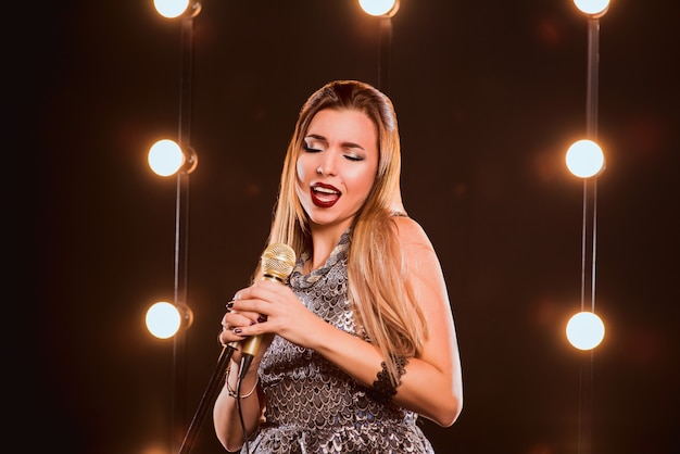 Uśmiechnięta Piękna Kobieta Z Mikrofonem śpiewająca Piosenkę Na Scenie W Karaoke
