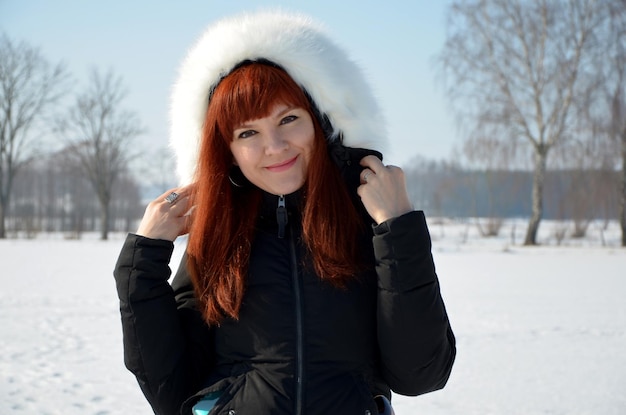 Uśmiechnięta piękna młoda kobieta w ciepłych ubraniach w winter park