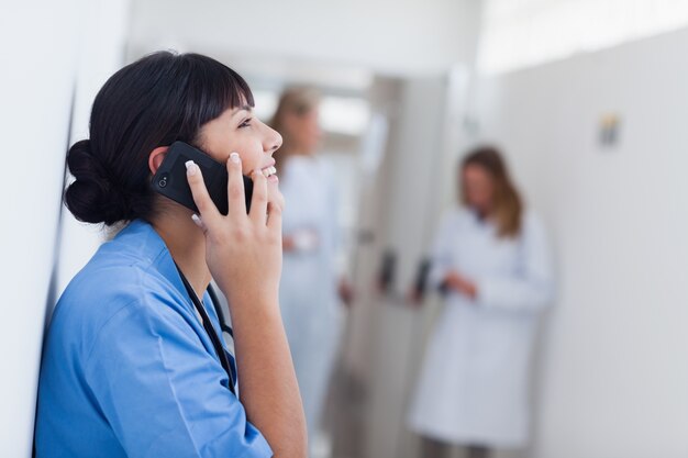 Uśmiechnięta pielęgniarka trzyma telefon komórkowego