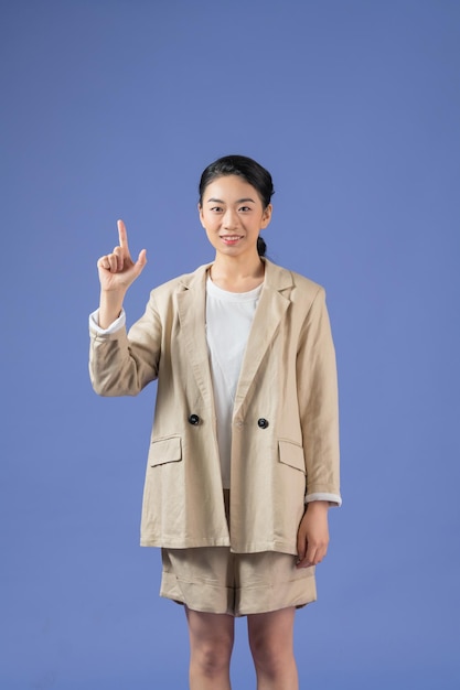 Uśmiechnięta podekscytowana kobieta pokazująca reklamę wskazującą palec stojący na fioletowym tle