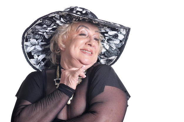 Uśmiechnięta starsza kobieta w czarnym kapeluszu pozuje na białym tle