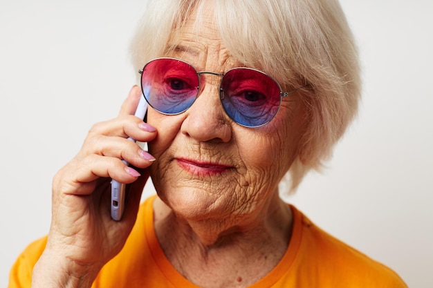 Uśmiechnięta starsza kobieta w zwykłych okularach przeciwsłonecznych tshirt rozmawia przez telefon emocje zbliżenia
