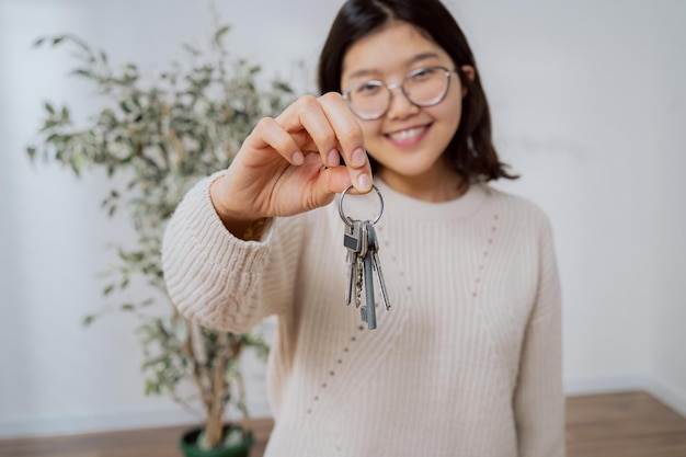 Uśmiechnięta szczęśliwa młoda kobieta o azjatyckiej urodzie w okularach stoi w nowo zakupionym mieszkaniu