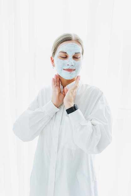 Zdjęcie uśmiechnięta twarz kobiety z maską nawilżającą na twarzy pielęgnacja skóry twarzy procedura piękności twarzy