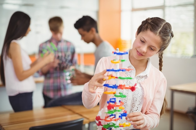 Uśmiechnięta uczennica bada model cząsteczki w laboratorium