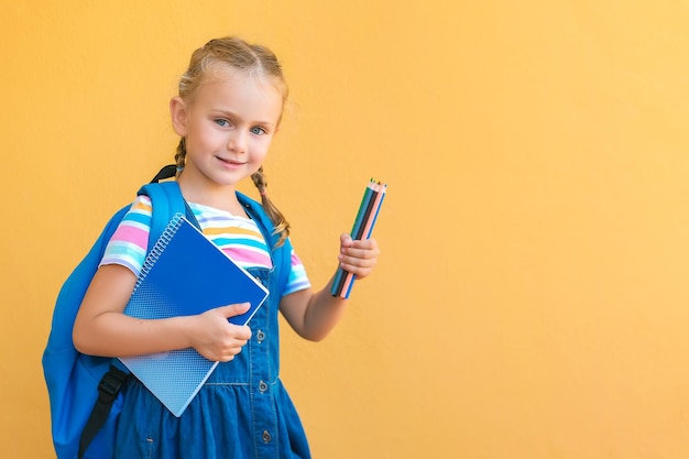 Uśmiechnięta Uczennica W Mundurku Szkolnym Trzyma Kolorowe Kredki Notatnik Plecak Transparent Kopia Przestrzeń Na żółtym Tle Reklama Przybory Szkolne I Artykuły Papiernicze Powrót Do Szkoły