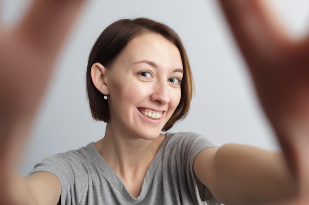 Uśmiechnięta Wesoła Dziewczyna Z Piegami Robi Selfie Wyciągając Ręce Do Aparatu