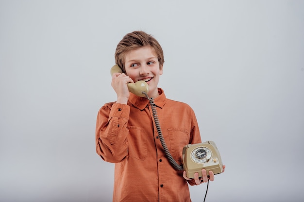 Zdjęcie uśmiechnięte dziecko rozmawiające na starym telefonie na białym tle