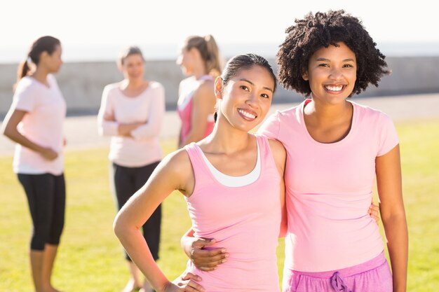 Uśmiechnięte młode kobiety ubrane na różowo dla raka piersi