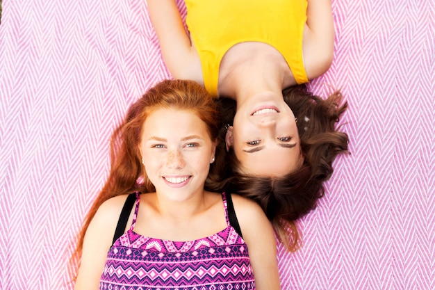 Zdjęcie uśmiechnięte nastolatki leżące na koce piknikowej.