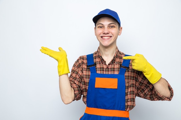 Uśmiechnięte punkty z boku młodego sprzątacza w mundurze i czapce z rękawiczkami