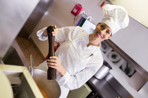 Zdjęcie uśmiechniętej kobiety kucharza narządzania jedzenie w kuchni