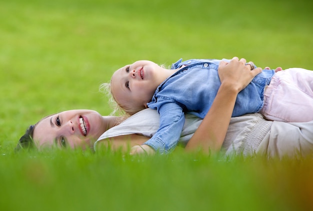 Uśmiechniętej matki łgarski puszek na trawie z ślicznym dzieckiem