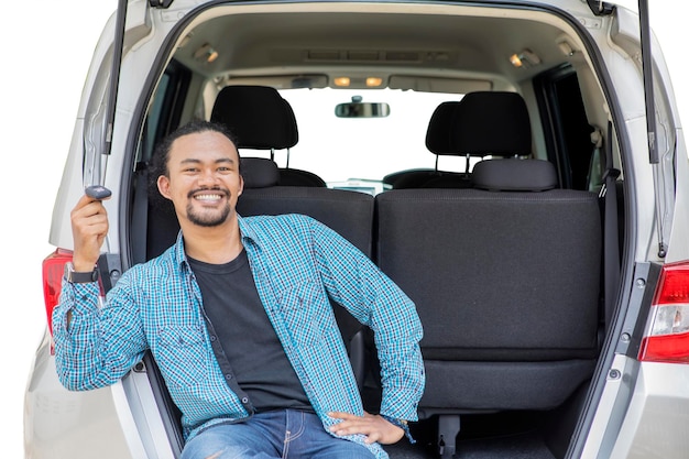 Uśmiechnięty Afro mężczyzna trzyma nowy kluczyk w bagażniku samochodu