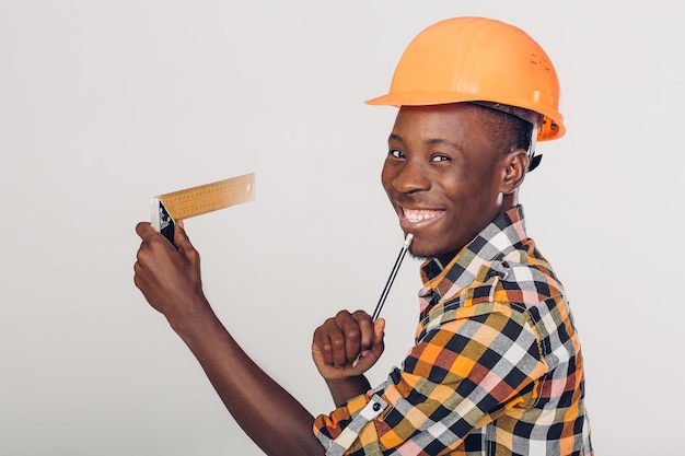 Uśmiechnięty Afroamerykański pracownik budowniczy używa linijki budowlanej