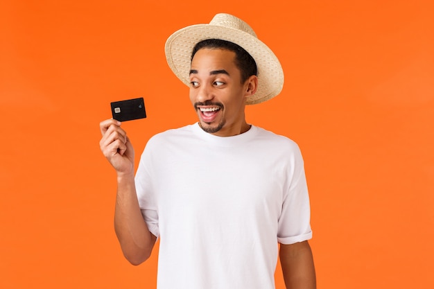 Uśmiechnięty Afroamerykański Przystojny Mężczyzna W Kapeluszu Patrzeje Kartę Kredytową