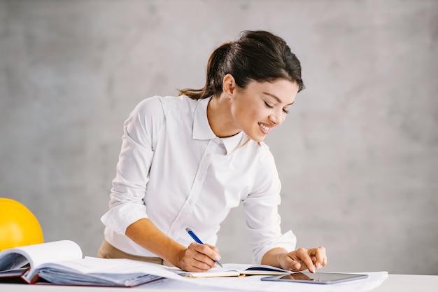 Uśmiechnięty architekt w biurze przewijający się na tablecie i pracujący nad projektem