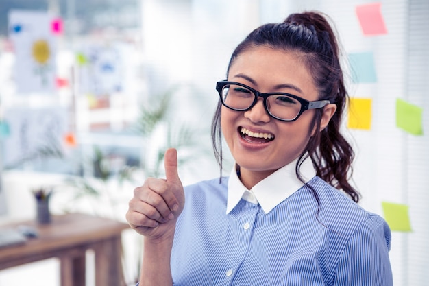 Uśmiechnięty Azjatycki bizneswoman pokazuje kciuk up w biurze