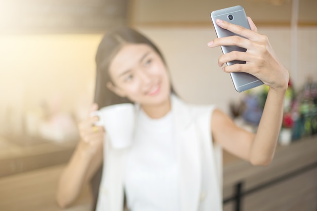 Uśmiechnięty Azjatycki dziewczyny selfie z filiżanką kawy w kawiarni